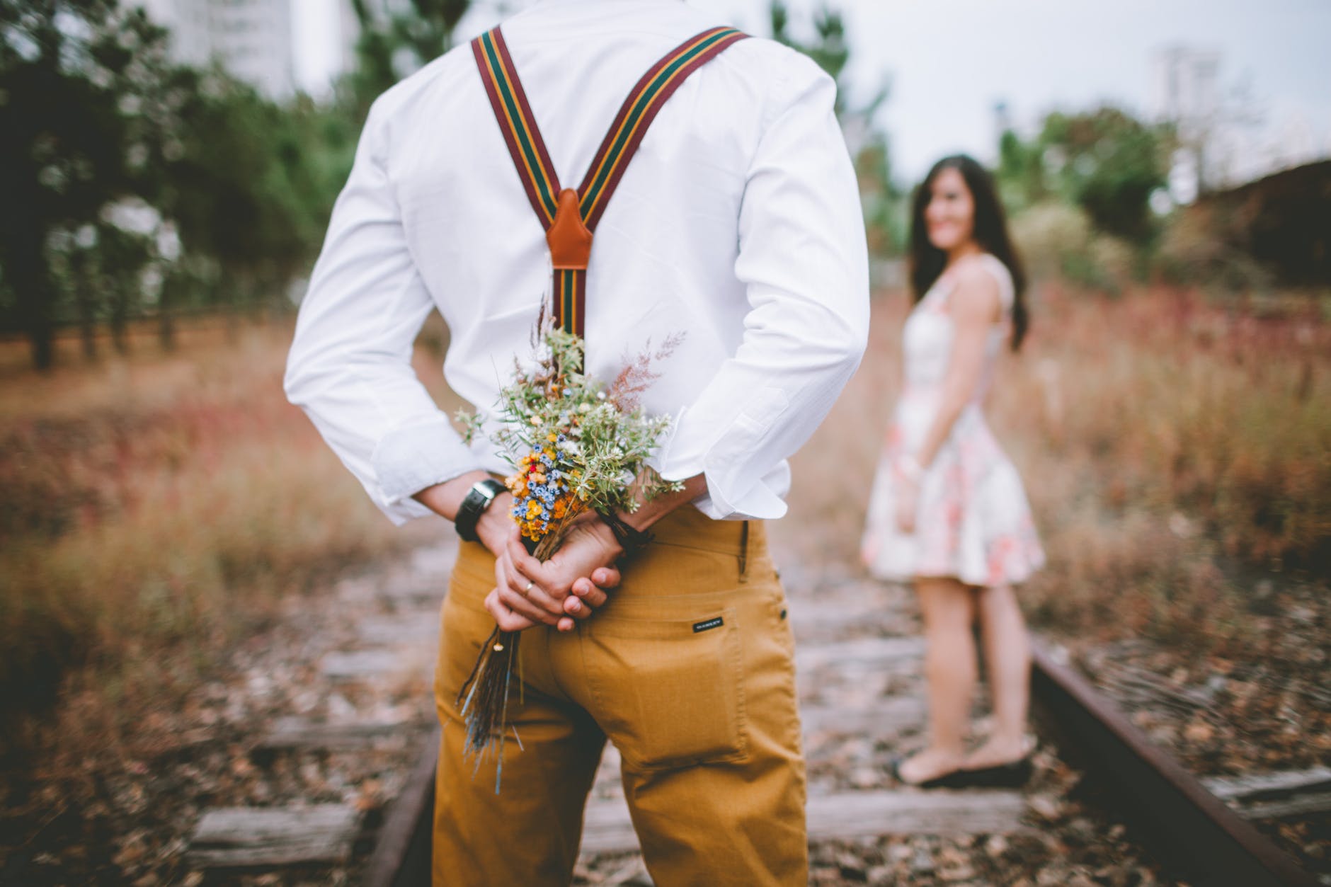 man holding flowers standing near woman